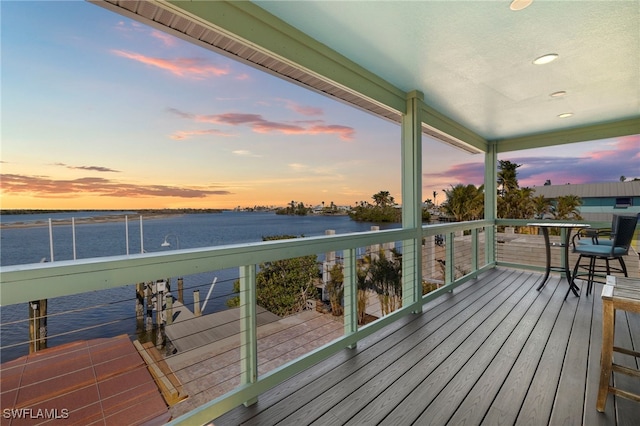 deck at dusk featuring a water view