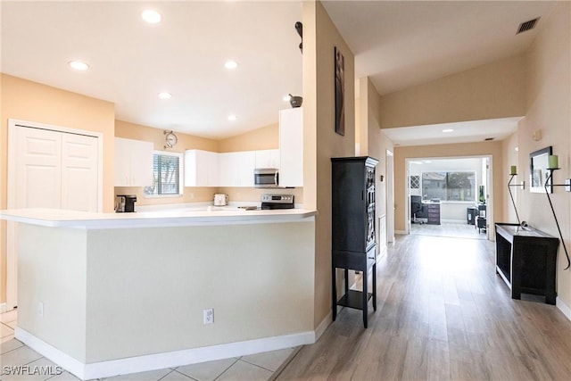 kitchen featuring stainless steel appliances, lofted ceiling, visible vents, and white cabinets