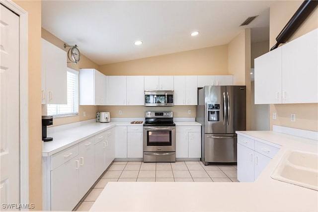 kitchen featuring white cabinets, stainless steel appliances, sink, vaulted ceiling, and light tile patterned floors