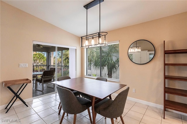 dining space featuring light tile patterned floors, baseboards, and vaulted ceiling