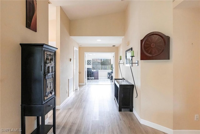 hall with visible vents, light wood-type flooring, and baseboards