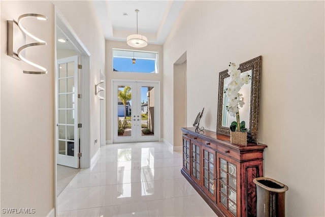 entrance foyer with french doors, a towering ceiling, and a tray ceiling