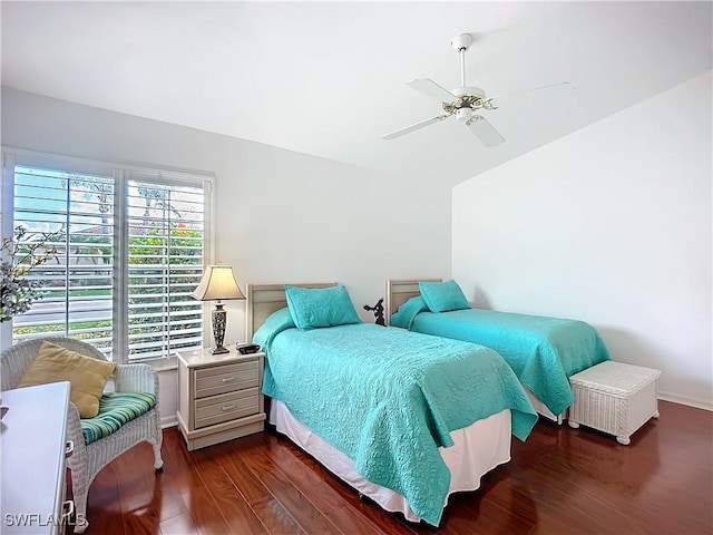 bedroom with dark wood-style floors, a ceiling fan, and baseboards