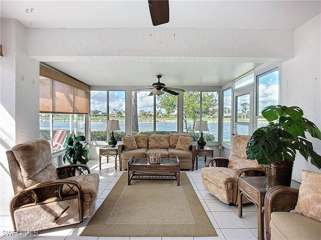 sunroom featuring a ceiling fan and a water view