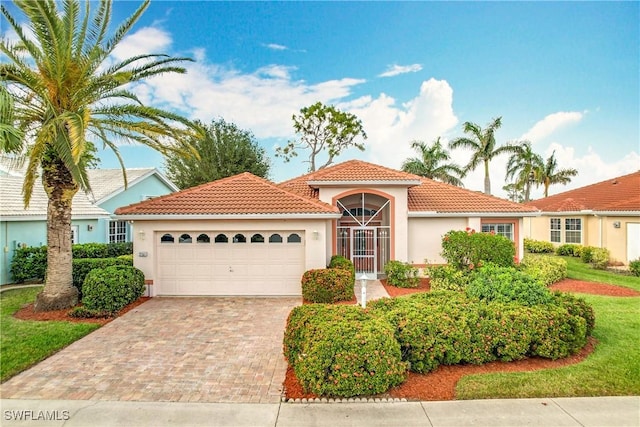 mediterranean / spanish-style house featuring a garage, decorative driveway, a tile roof, and stucco siding