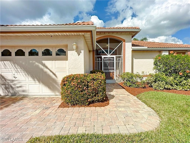 view of exterior entry featuring an attached garage, decorative driveway, and stucco siding