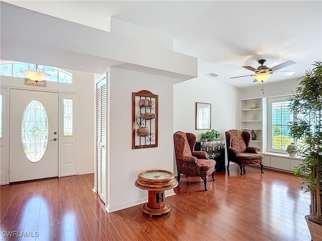 foyer entrance featuring baseboards, wood finished floors, visible vents, and a ceiling fan