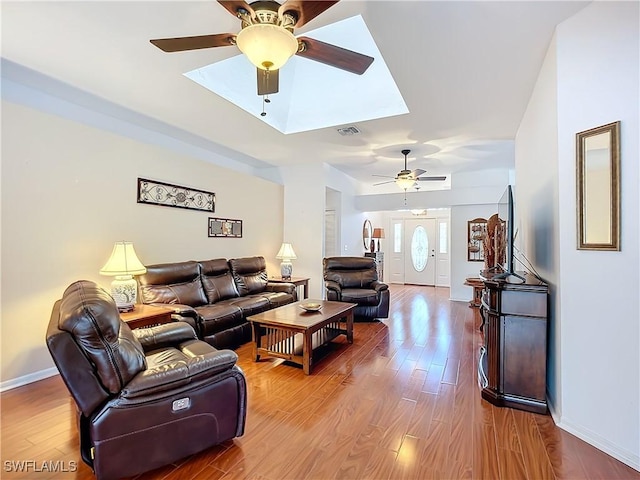 living room featuring a ceiling fan, visible vents, baseboards, and wood finished floors