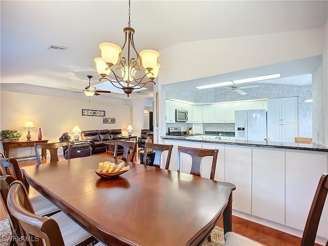 dining space featuring lofted ceiling, visible vents, and ceiling fan with notable chandelier