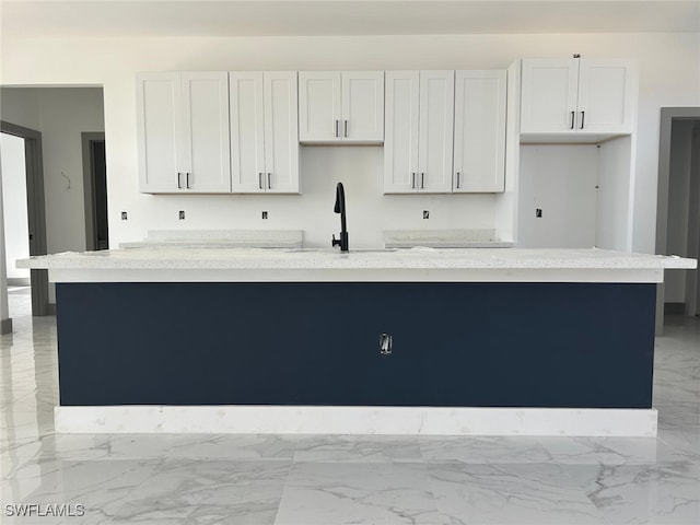 kitchen featuring sink, white cabinets, and a center island with sink