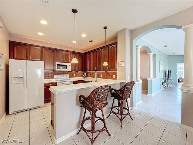 kitchen featuring white appliances, pendant lighting, ornate columns, and kitchen peninsula