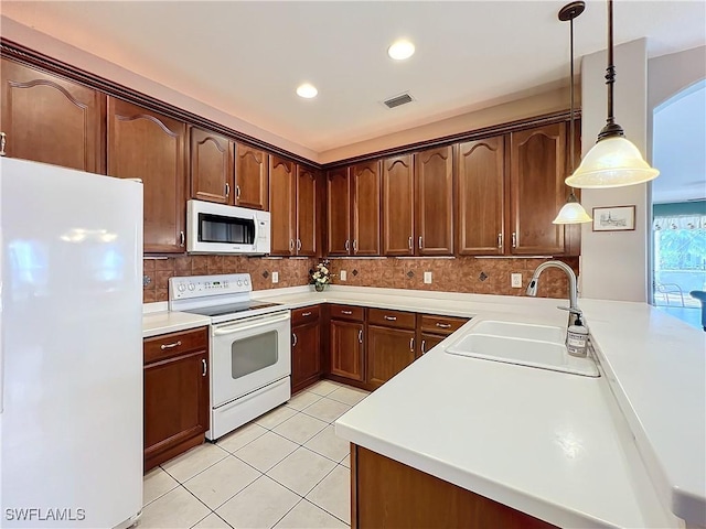 kitchen featuring sink, backsplash, white appliances, and hanging light fixtures