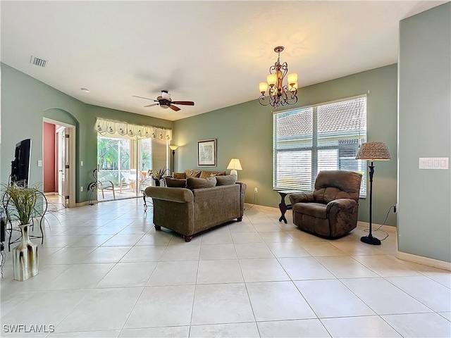 tiled living room with ceiling fan with notable chandelier