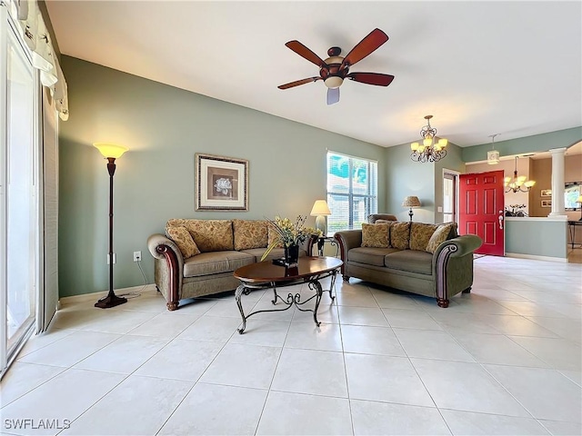 living room with ceiling fan with notable chandelier, ornate columns, and light tile patterned floors