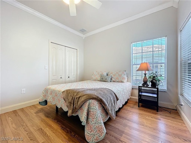 bedroom with ceiling fan, crown molding, wood-type flooring, and a closet