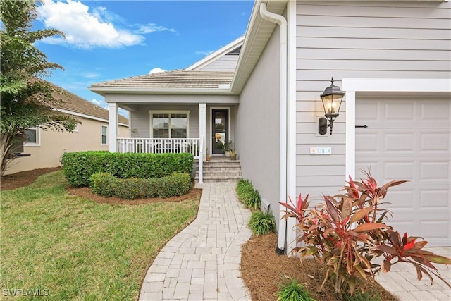 view of exterior entry with a yard and covered porch