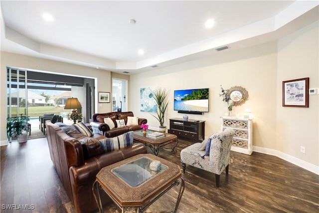 living room with dark hardwood / wood-style floors and a raised ceiling