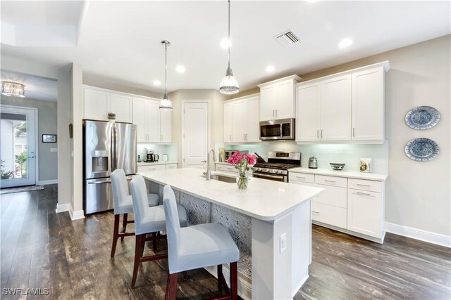 kitchen featuring stainless steel appliances, hanging light fixtures, sink, and white cabinets