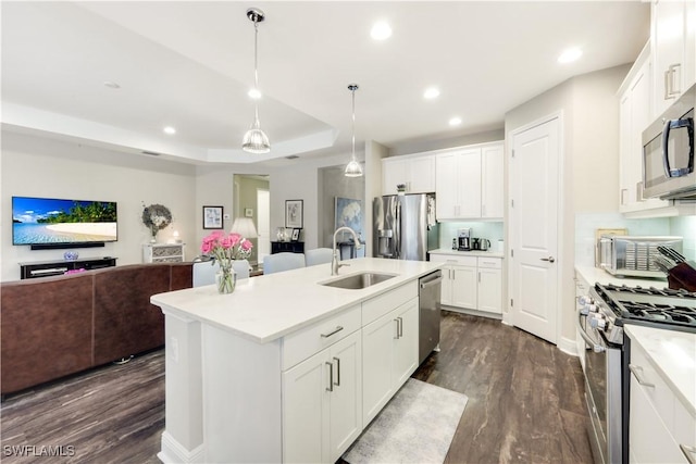 kitchen featuring sink, appliances with stainless steel finishes, an island with sink, pendant lighting, and white cabinets