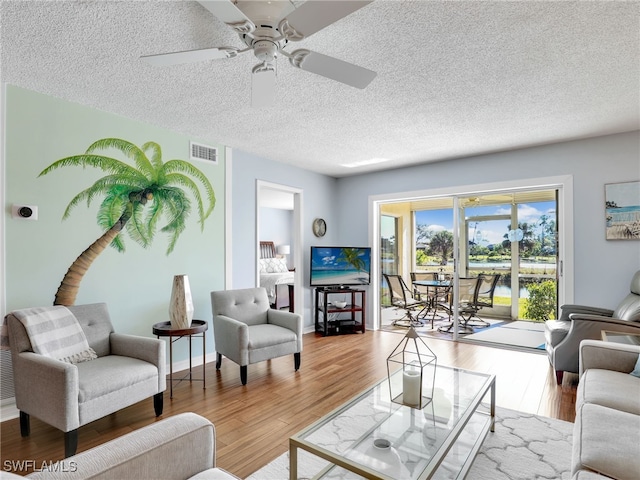 living room featuring ceiling fan, a textured ceiling, and hardwood / wood-style floors