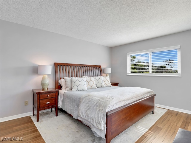 bedroom with a textured ceiling and light hardwood / wood-style floors