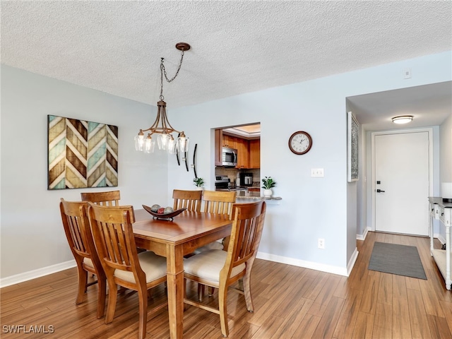 dining space featuring a notable chandelier, a textured ceiling, and hardwood / wood-style flooring