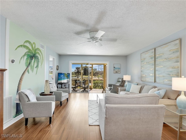 living room featuring ceiling fan, a textured ceiling, and light wood-type flooring