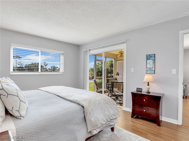 bedroom featuring wood-type flooring, a textured ceiling, and access to outside