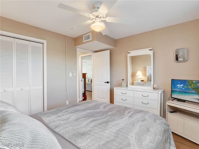 bedroom with light wood-type flooring, ceiling fan, and a closet