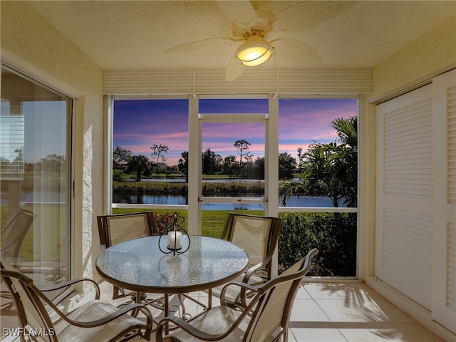 sunroom / solarium featuring ceiling fan and a water view