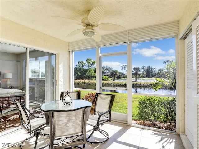 sunroom / solarium with ceiling fan, a water view, and plenty of natural light