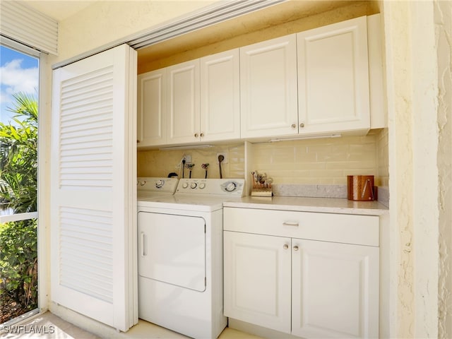 clothes washing area featuring cabinets and washer and clothes dryer