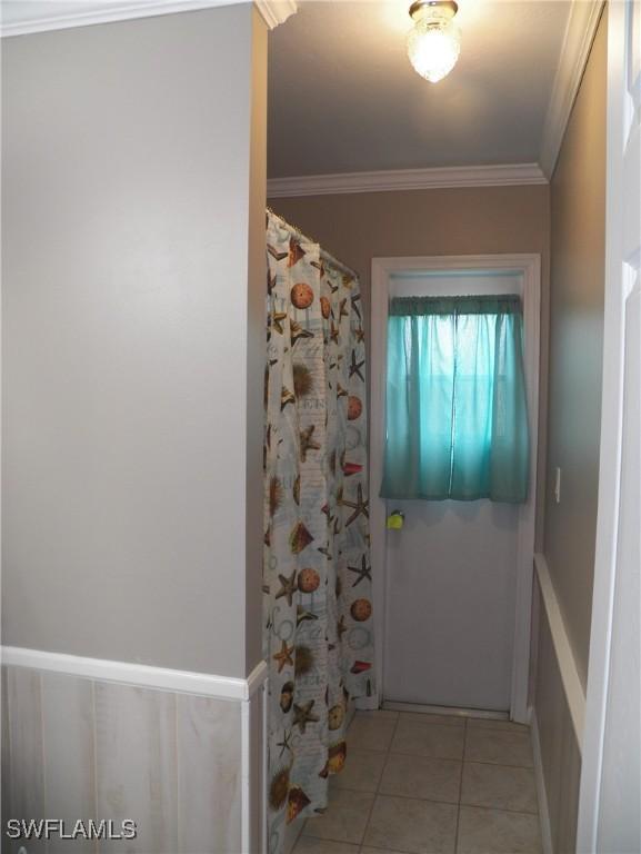 doorway to outside featuring light tile patterned floors and ornamental molding