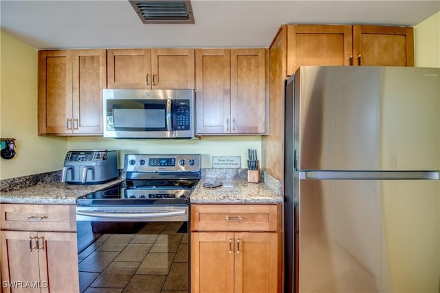 kitchen with light stone counters and appliances with stainless steel finishes