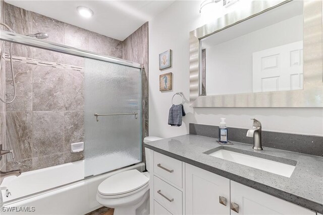 full bathroom featuring shower / bath combination with glass door, vanity, and toilet