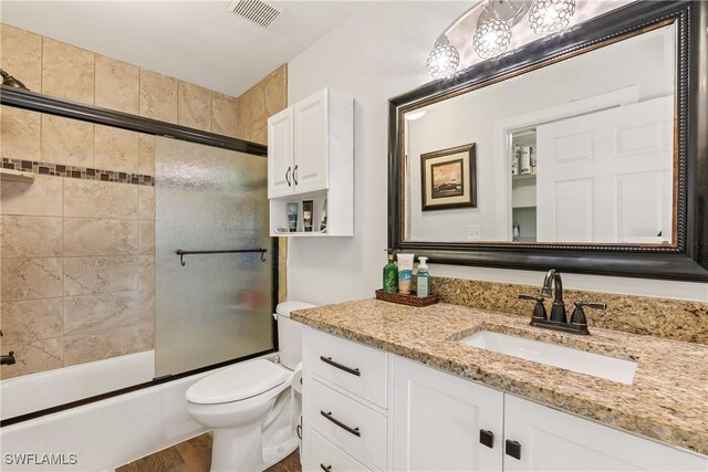 full bathroom featuring toilet, combined bath / shower with glass door, wood-type flooring, and vanity