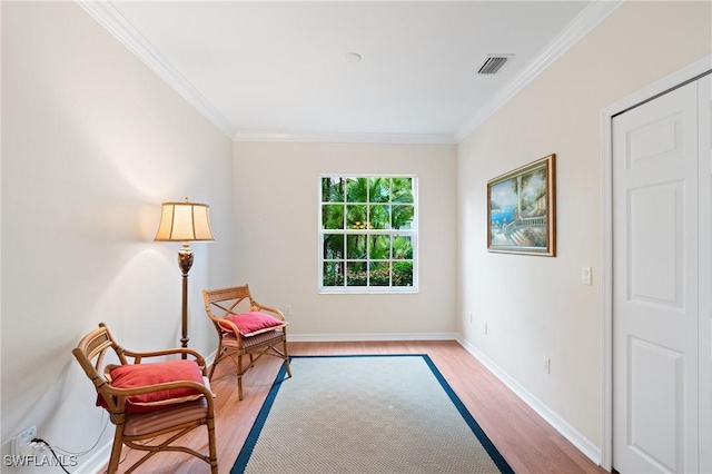 living area with crown molding and light hardwood / wood-style flooring