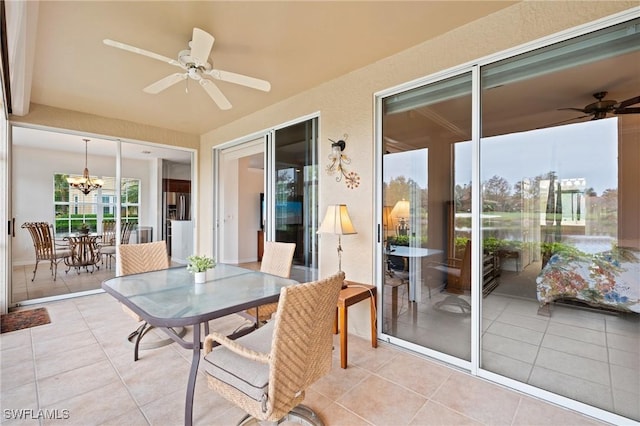 sunroom featuring ceiling fan with notable chandelier