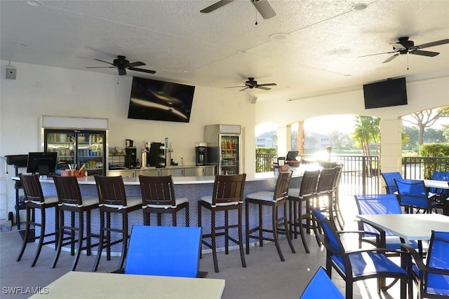 view of patio featuring ceiling fan and a bar