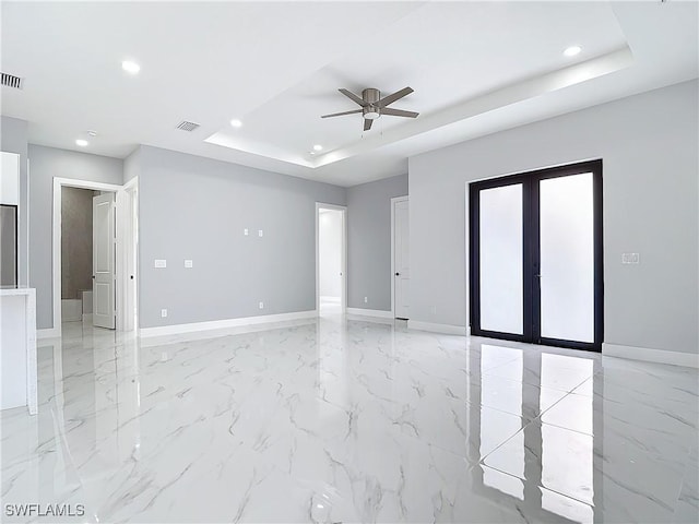 spare room with a raised ceiling, ceiling fan, and french doors