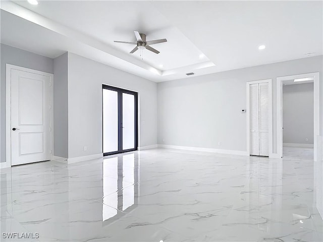 spare room featuring french doors, ceiling fan, and a raised ceiling