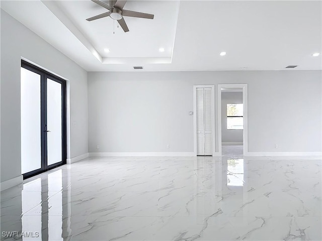 spare room featuring a raised ceiling, ceiling fan, and french doors