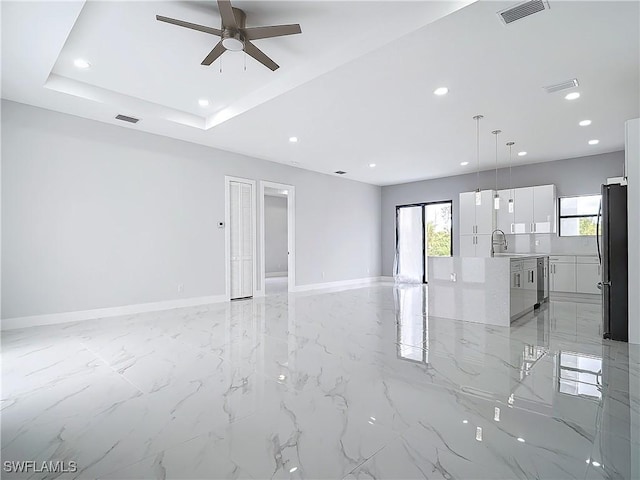 spare room featuring ceiling fan, a tray ceiling, and sink