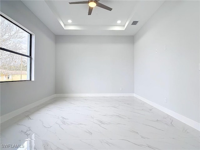 empty room featuring ceiling fan and a tray ceiling