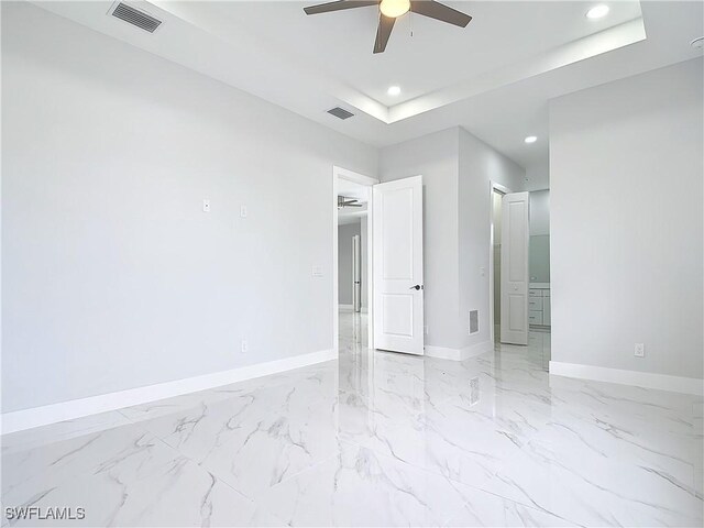 spare room with a raised ceiling and ceiling fan