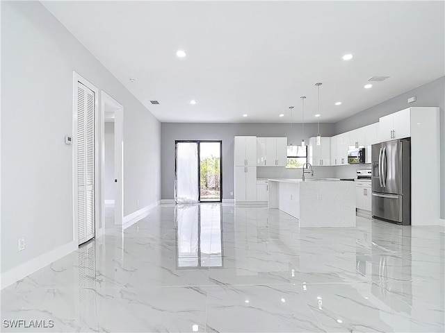 kitchen with sink, appliances with stainless steel finishes, pendant lighting, a kitchen island with sink, and white cabinets