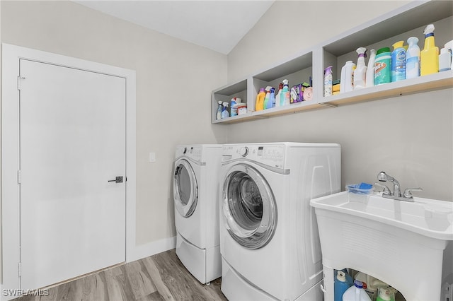 laundry room with sink, washing machine and clothes dryer, and light hardwood / wood-style floors