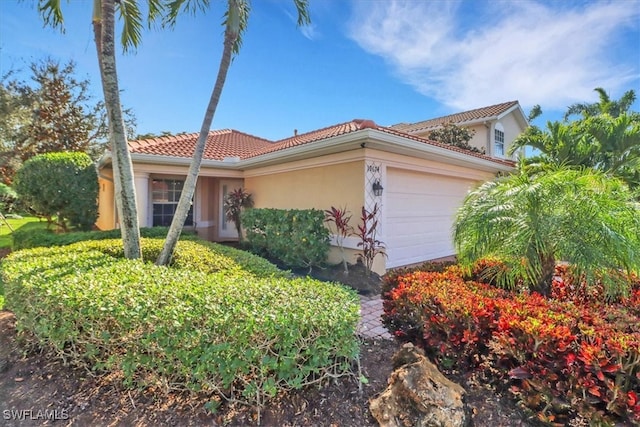 mediterranean / spanish-style house with a garage, a tile roof, and stucco siding