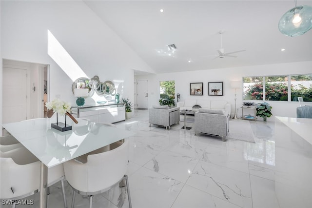 dining space with ceiling fan and high vaulted ceiling