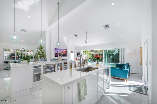 kitchen featuring vaulted ceiling, sink, white cabinets, and an island with sink